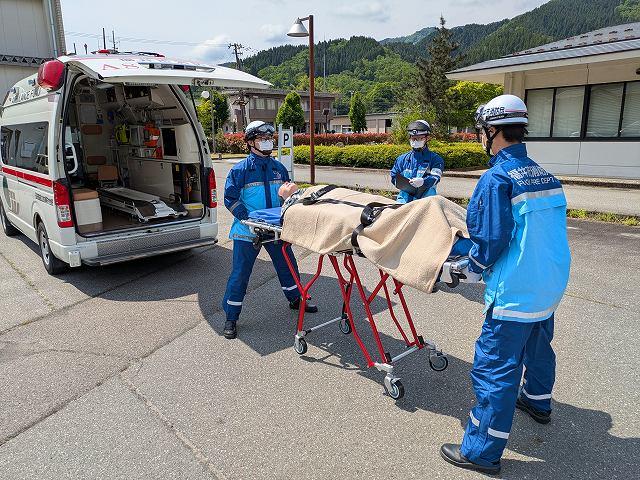 ストレッチャーを操作する救急隊員とそれを評価する指導救命士